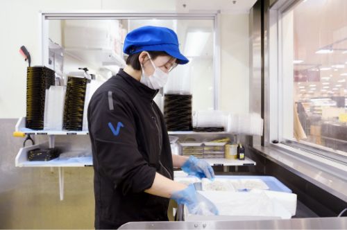 水産部門の女性パートタイマーがバックヤードでシラスのパック詰めをする様子